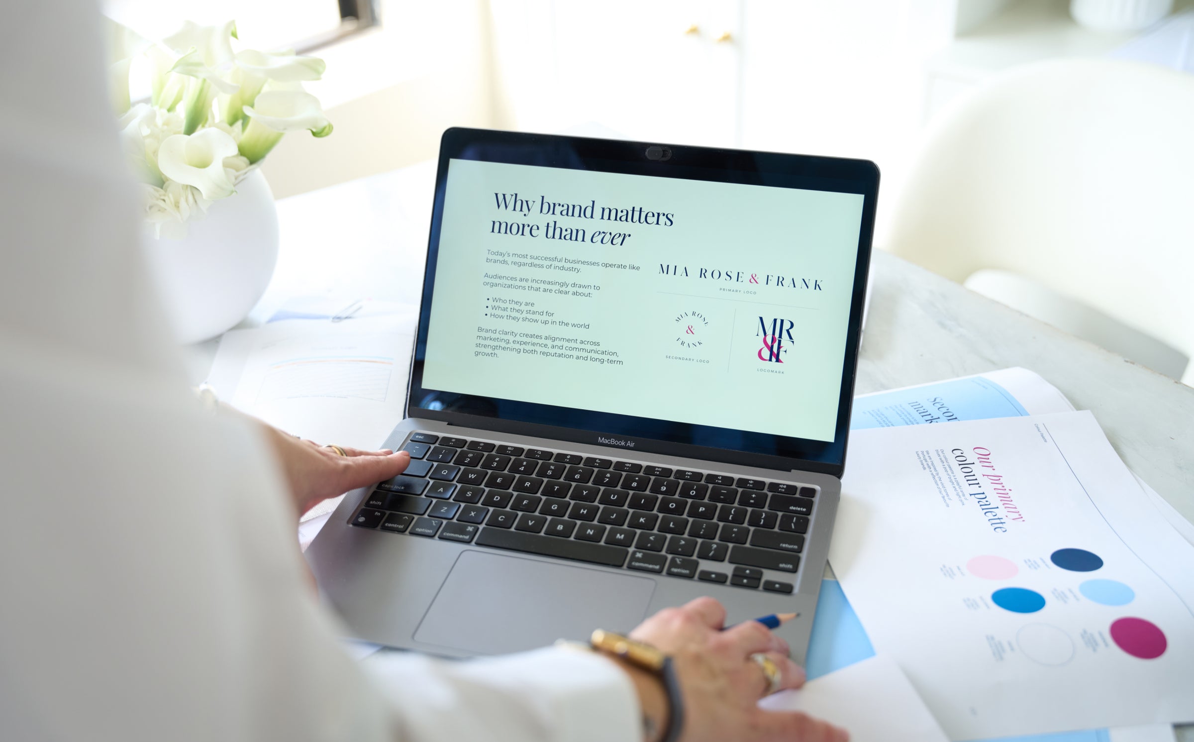 Person using a laptop with a screen displaying a brand strategy presentation.